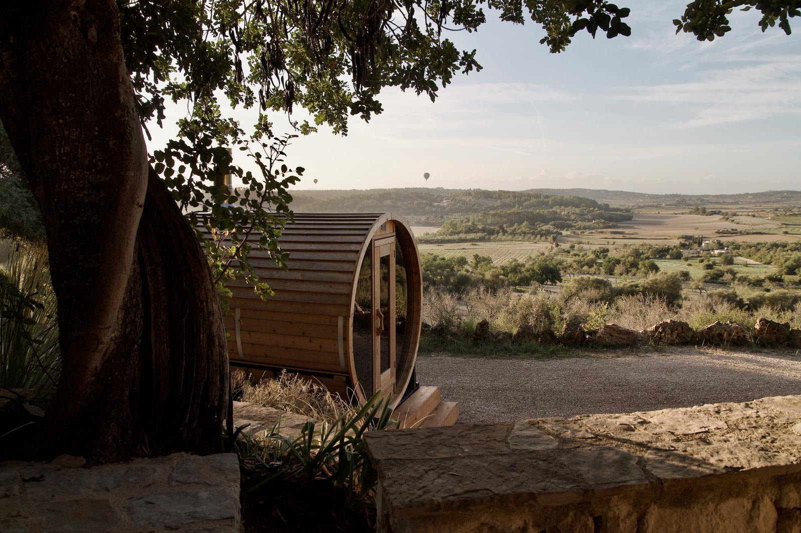 Wooden barrel sauna on a stone ledge with a scenic landscape view
